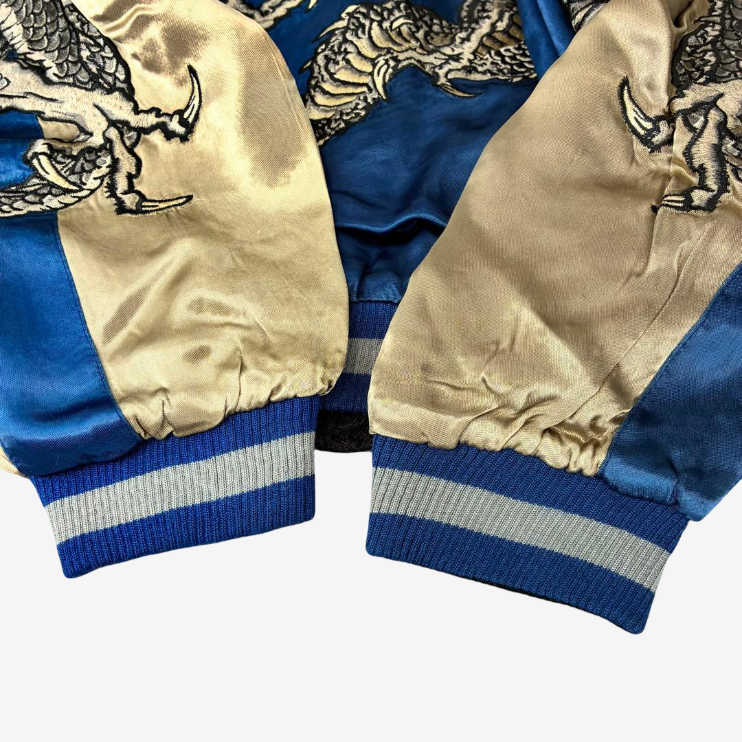Close-up of blue and champagne gold reversible Sukajan jacket sleeves featuring twin dragon embroidery and striped ribbed cuffs.